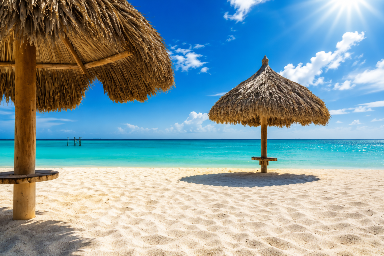 Thatched palapas on a quiet Aruba beach with turquoise sea